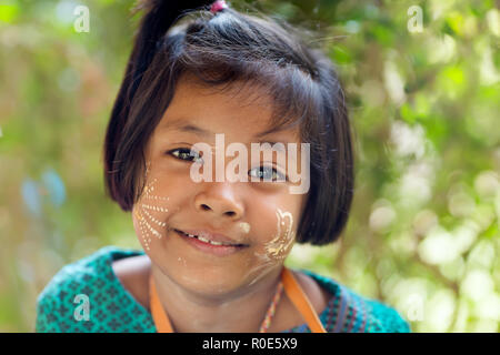 SANGHLABURI, THAILAND, JANUARY 24, 2016 : A Thai little girl with Burmese Thanaka cosmetic powder is posing near a temple in Sanghlaburi, Thailand Stock Photo