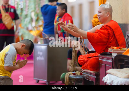 SANGKHLABURI, THAILAND, JANUARY 24, 2016 :  A skilled Buddhist monk is blessing a man  by throwing a rosary necklace around his neck in the Wat Wang W Stock Photo