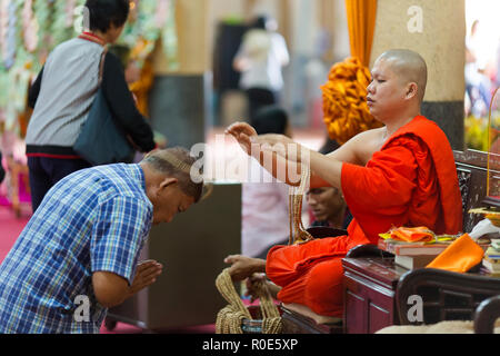 SANGKHLABURI, THAILAND, JANUARY 24, 2016 :  A skilled Buddhist monk is blessing a man  by throwing a rosary necklace around his neck in the Wat Wang W Stock Photo