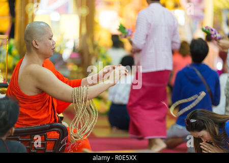 SANGKHLABURI, THAILAND, JANUARY 24, 2016 :  A skilled Buddhist monk is blessing a woman  by throwing a rosary necklace around his neck in the Wat Wang Stock Photo