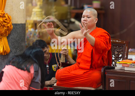 SANGKHLABURI, THAILAND, JANUARY 24, 2016 : A skilled Buddhist monk is blessing a woman by throwing a rosary necklace around his neck in the Wat Wang W Stock Photo