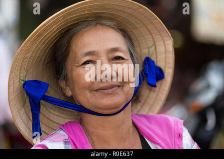 SAIGON, VIETNAM, FEBRUARY 26, 2015 : Portrait of a seller senior woman wearing traditional conical hat in the streets of Saigon (Ho Chi Minh), Vietnam Stock Photo