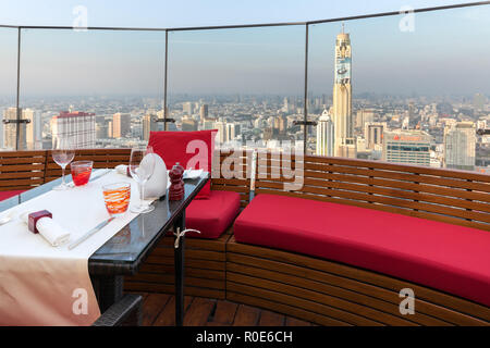 BANGKOK, THAILAND, JANUARY 14, 2015 : Restaurant table with view on the cityscape at the Red Sky Rooftop of the Centara hotel in Bangkok, Thailand. Stock Photo