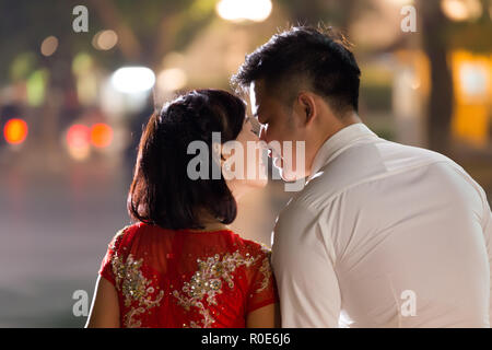 HANOI, VIETNAM, DECEMBER 15, 2014: Two young married people are exchanging a love kiss in evening at the city center's Hoan Kiem lake in Hanoi city, V Stock Photo