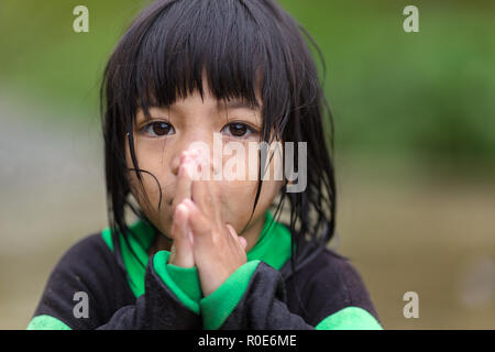 BANAUE, PHILIPPINES, DECEMBER 04 : A young unidentified Filipino little girl is praying under the rain in the village of Banaue, north Luzon, Philippi Stock Photo