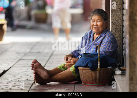 BANGKOK, THAILAND, DECEMBER 16, 2012 : Thai woman beggar sitting on the sidewalk in the Chinatown district in Bangkok, Thailand. Stock Photo