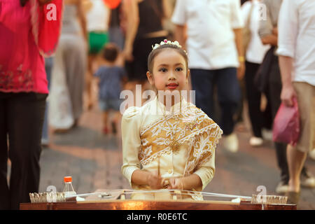 CHIANG MAI, THAILAND, FEBRUARY 26, 2012: A little girl dressed in traditional clothes is playing dulcimer instrument in the street during the week-end Stock Photo