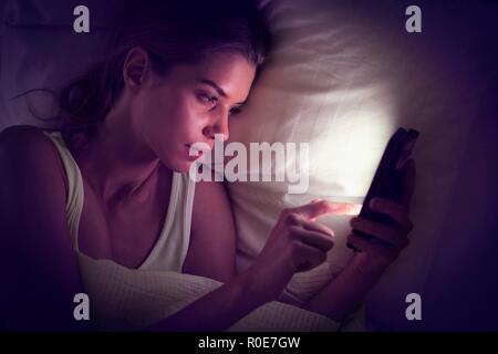 Young woman using digital tablet in bed. Stock Photo