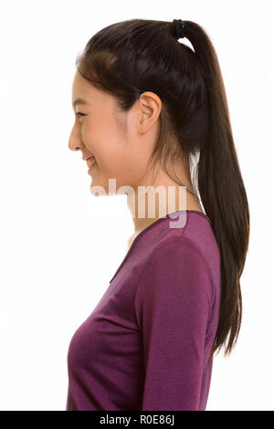 Profile view of young happy Asian teenage girl smiling Stock Photo