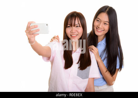 Two young happy Asian teenage girls smiling and taking selfie wi Stock Photo