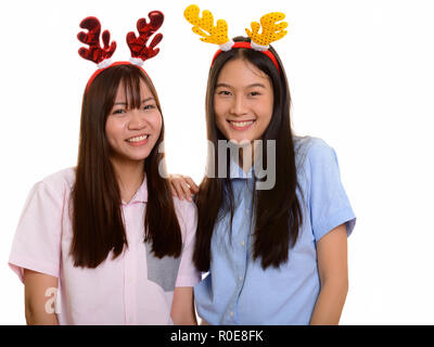 Two young happy Asian teenage girls smiling ready for Christmas Stock Photo