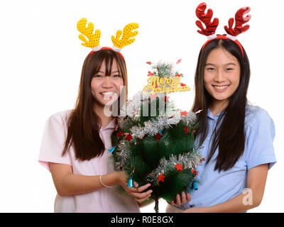 Two young happy Asian teenage girls smiling holding Merry Christ Stock Photo