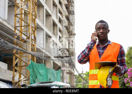 Thoughtful young black African man construction worker talking o Stock Photo