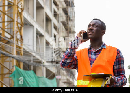 Thoughtful young black African man construction worker talking o Stock Photo
