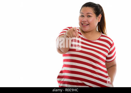 Studio shot of young happy fat Asian woman smiling while pointin Stock Photo