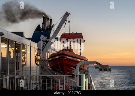 Closeup of lifeboats on a Cruise Ship with smoking chimney Stock Photo