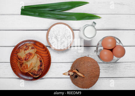 Akok Kedut, egg, coconut, flour , coconut milk and  Pandan leaf on wooden background. Akok Kedut is a traditional dish in Malaysia especially East Coa Stock Photo