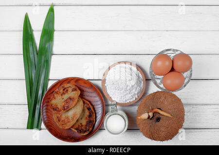 Akok Kedut, egg, coconut, flour , coconut milk and  Pandan leaf on wooden background. Akok Kedut is a traditional dish in Malaysia especially East Coa Stock Photo