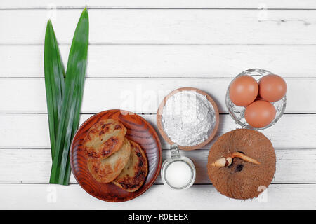 Akok Kedut, egg, coconut, flour , coconut milk and  Pandan leaf on wooden background. Akok Kedut is a traditional dish in Malaysia especially East Coa Stock Photo