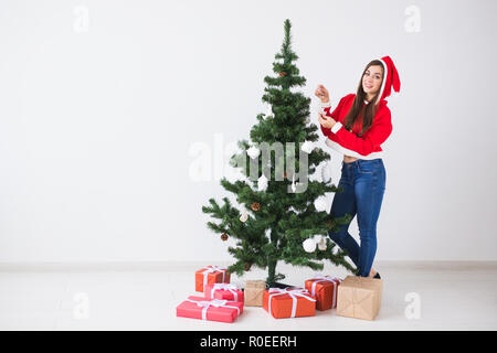 Winter holidays and people concept - Loving couple hanging decorations on Christmas tree on white room background with copy space Stock Photo