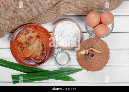 Akok Kedut, egg, coconut, flour , coconut milk and  Pandan leaf on wooden background. Akok Kedut is a traditional dish in Malaysia especially East Coa Stock Photo