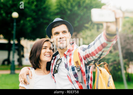 Horizontal portrait of smiling cheerful female and male holding camera in hand, photographing themselves, while resting after long trip by bus. Family Stock Photo