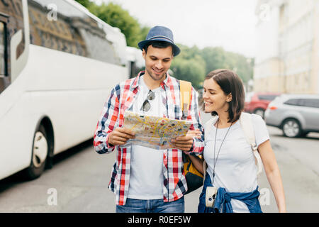 Happy tourists or travellers looking with happy expression in map, being glad to see one more place to reach, having good mood after wonderful trip on Stock Photo