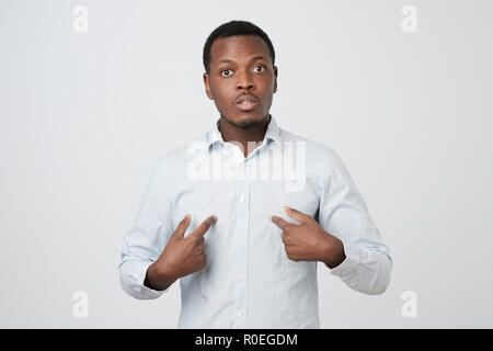 Young african man pointing at himself, making excuses or verbally defending, Stock Photo