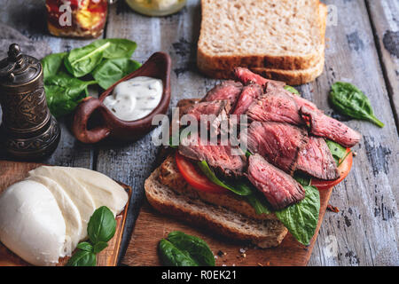Steak sandwich, sliced roast beef, cheese,spinach leaves,tomato Stock Photo