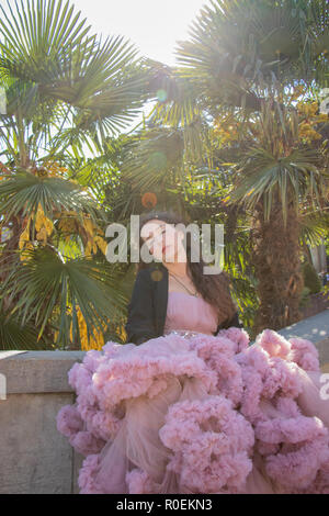 Beautiful hipster girl dressed in a pink ballroom dress with a palm trees in the background Stock Photo