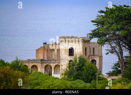 An old derelict castle sits high on a hill top overlooking the sea Stock Photo