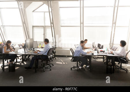 Diverse employees focused on working on desktops in shared offic Stock Photo