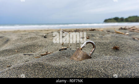 Golden padlock on a dark sand beach Stock Photo