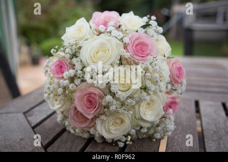 Brides wedding Day bouquet of Pink and Cream roses sitting on a table outside in daylight Stock Photo