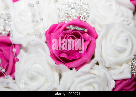 Engagement ring sitting in the brides wedding bouquet of roses Stock Photo
