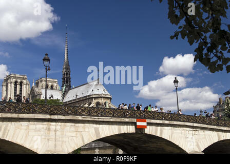 Tourists view the 'love padlocks' on the Pont de l'Archeveche (Archbishop's Bridge) railings, next to Notre Dame cathedral in Paris, France. Stock Photo