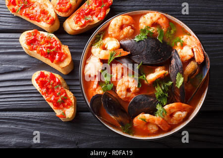 Bouillabaisse soup with seafood and fish close-up in a bowl served with toasts on the table. Horizontal top view from above Stock Photo