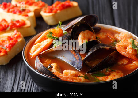 Bouillabaisse soup with seafood and fish close-up in a bowl served with toasts on the table. horizontal Stock Photo