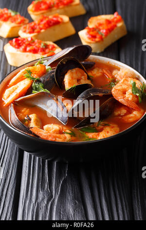 Traditional tomato seafood soup with shrimps, fish fillet and mussels closeup in a bowl on the table. vertical Stock Photo