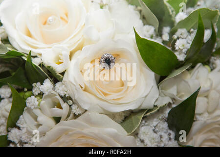 Engagement ring sitting in the brides wedding bouquet of roses Stock Photo