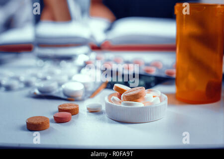 Close-up view on the pills in bottle's cap laying on the table Stock Photo