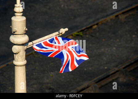 Union flag flying from horizontal strut on pole at railway station, England Stock Photo