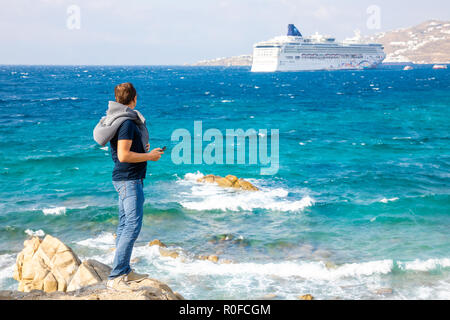 Young man looking on cruise ship, vacation at the colorfull town of Mikonos, Greece Stock Photo