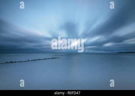 clouds effect on the beach with stones against surf in blue tint Stock Photo