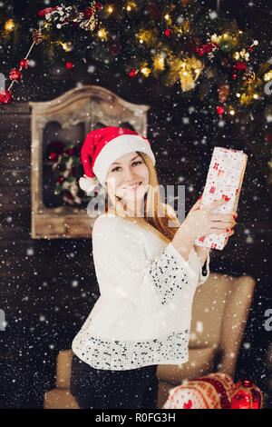 Happy woman in santa hat holding present box. Stock Photo