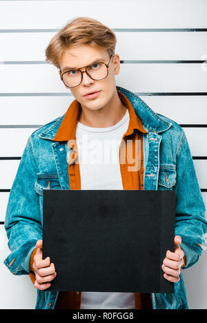 handsome hipster holding empty prison board while standing in front of police line up Stock Photo