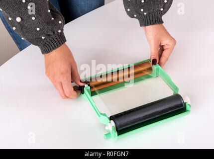 Woman adjusting the ribbon on the cartridge or spools for a photographic printer over a white table in a close up on her hands Stock Photo