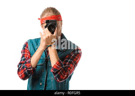concentrated hipster male photographer in denim vest and checkered shirt shooting on camera isolated on white Stock Photo