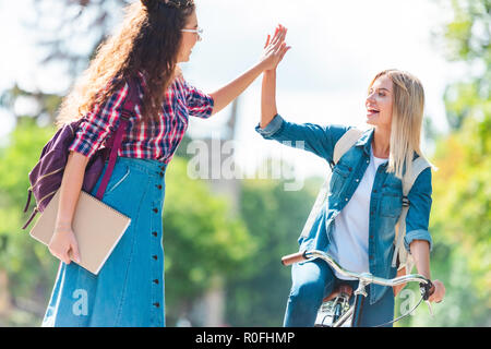 happy students giving high five to each other in park Stock Photo