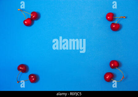 Blue background with cherries in the corners and copy space seen from above. flat lay Stock Photo